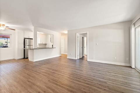 the living room and kitchen of an apartment with wood flooring